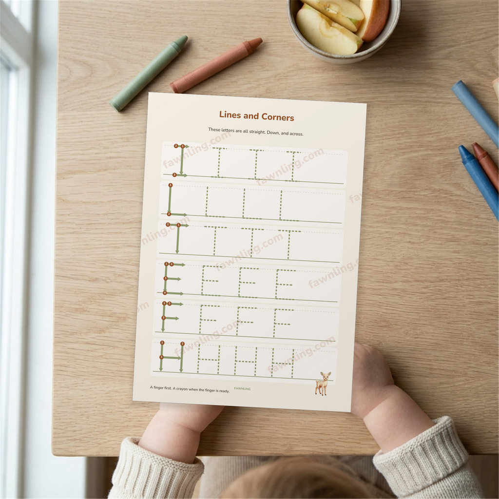 A child's hands at a table with a printed letter practice page in front of them